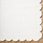 The Mystique Scalloped Wool Rug by Surya elegantly adorns the wooden floor with its off-white premium design.