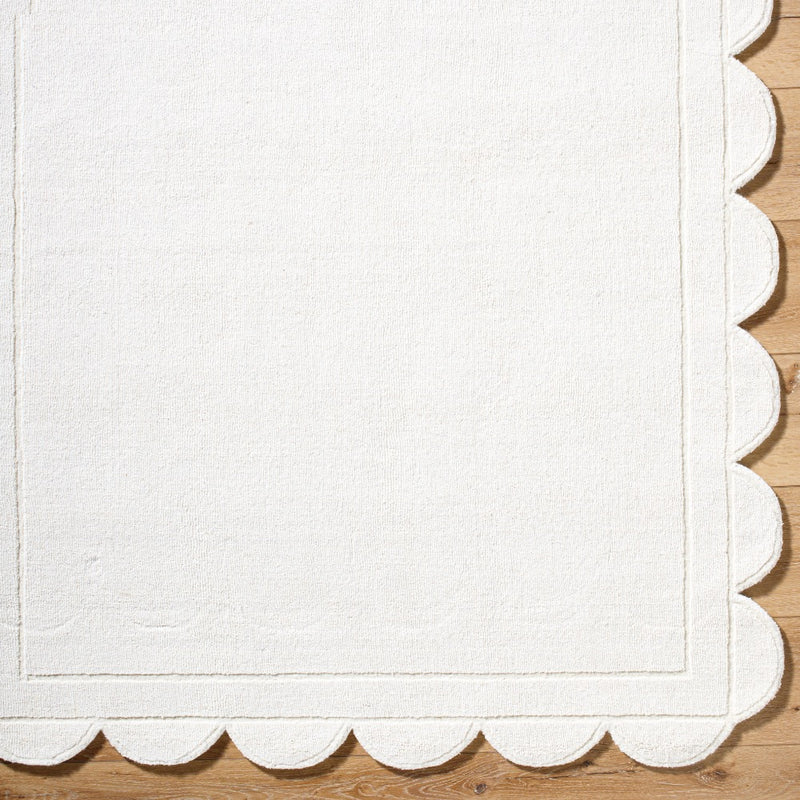 The Mystique Scalloped Wool Rug by Surya elegantly adorns the wooden floor with its off-white premium design.