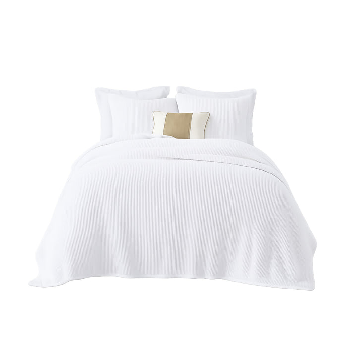 A neatly made bed with India's Heritage White Mandalay Coverlet, white pillows, and a beige accent pillow.