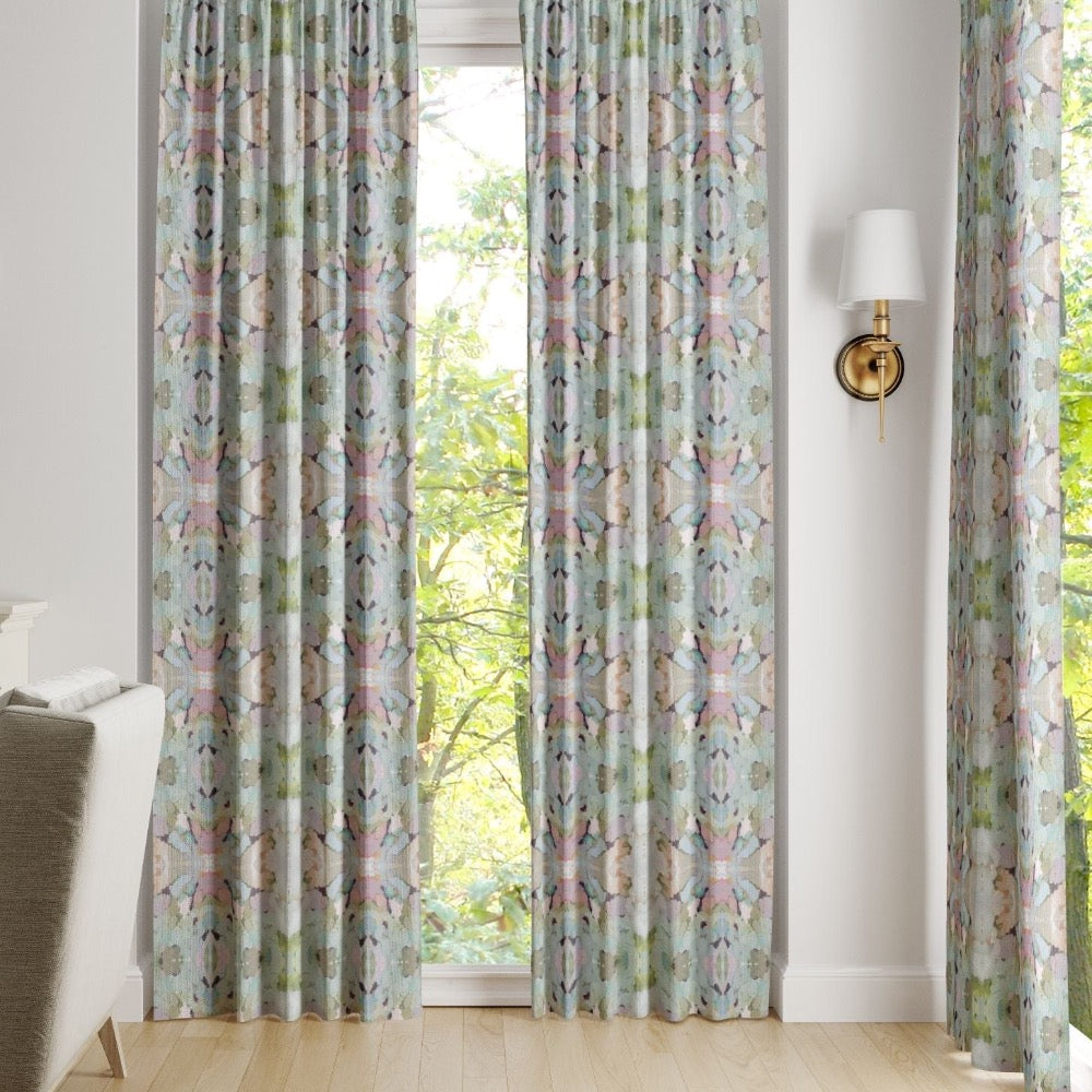 Martini Olives Curtain Panels by Laura Park Designs hang by a window, letting in natural light near an armchair.