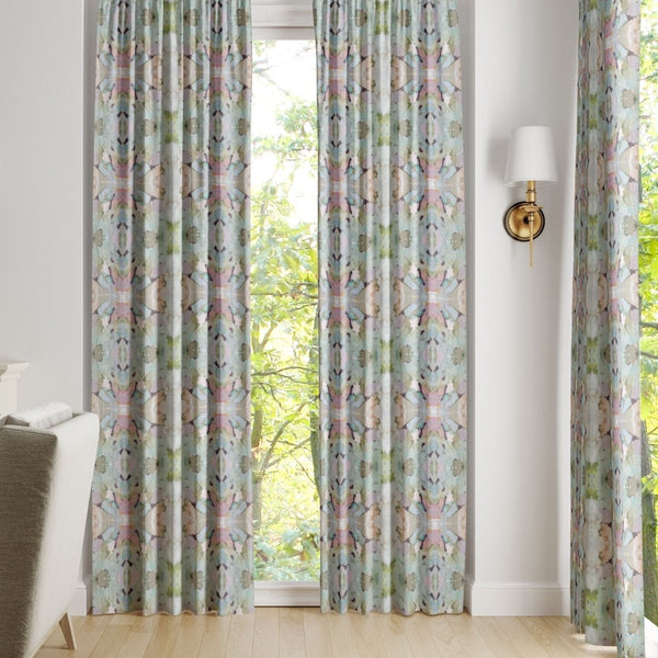 Martini Olives Curtain Panels by Laura Park Designs hang by a window, letting in natural light near an armchair.