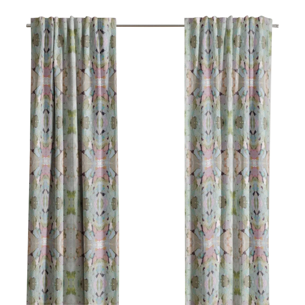 Martini Olives Curtain Panels by Laura Park Designs hang by a window, letting in natural light near an armchair.