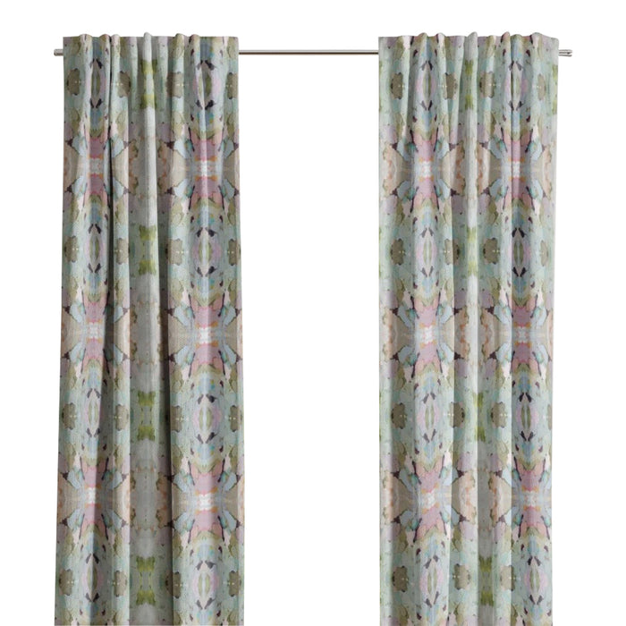 Martini Olives Curtain Panels by Laura Park Designs hang by a window, letting in natural light near an armchair.