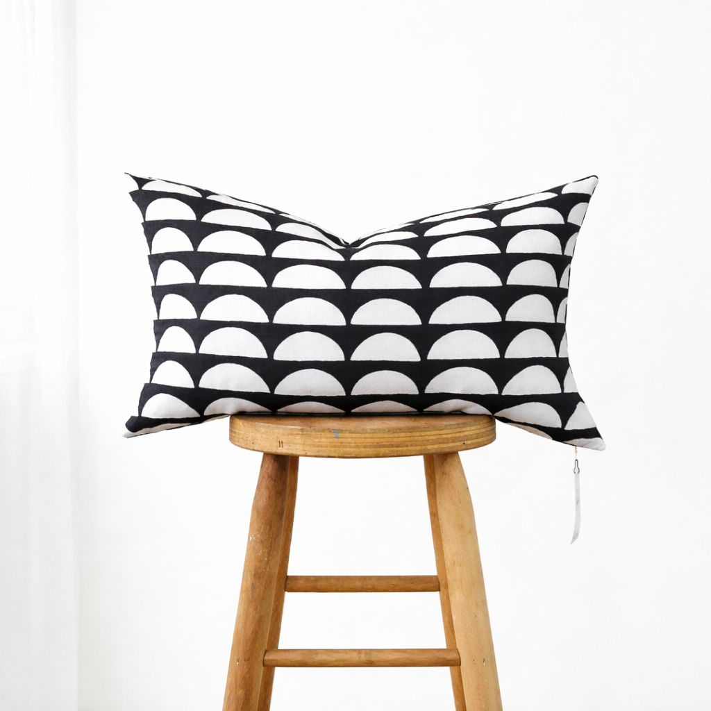 Muse Textiles Dark Gray + White Half Moons Lumbar Pillow, hand-crafted and shown on a wooden stool against white.