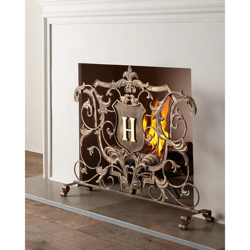 Dr. Livingstone, I Presume's Light Burnished Gold Fireplace Screen with "H" shield and Fleur de Lis, in front of a lit fire.