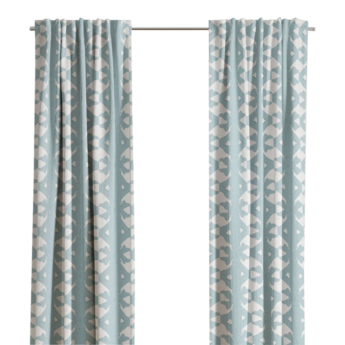 Laura Park Designs' Palm Mist Curtain Panels in light blue with a white geometric pattern hang by a window.