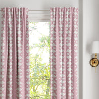Palm Rose Curtain Panels by Laura Park Designs frame the window; trees are visible, with a wall sconce on the right.
