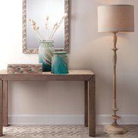 Decorative setup with a wooden table, vases, and a floor lamp against a neutral wall.