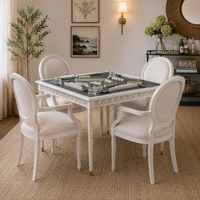 The warmly lit living room features Woodbridge’s Upholstered Newport Game Table with mahjong tiles and four cream chairs.