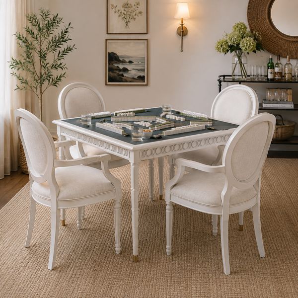 The warmly lit living room features Woodbridge’s Upholstered Newport Game Table with mahjong tiles and four cream chairs.