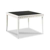 A square white table with a black top and decorative carved apron, shown on a white background with a soft shadow.