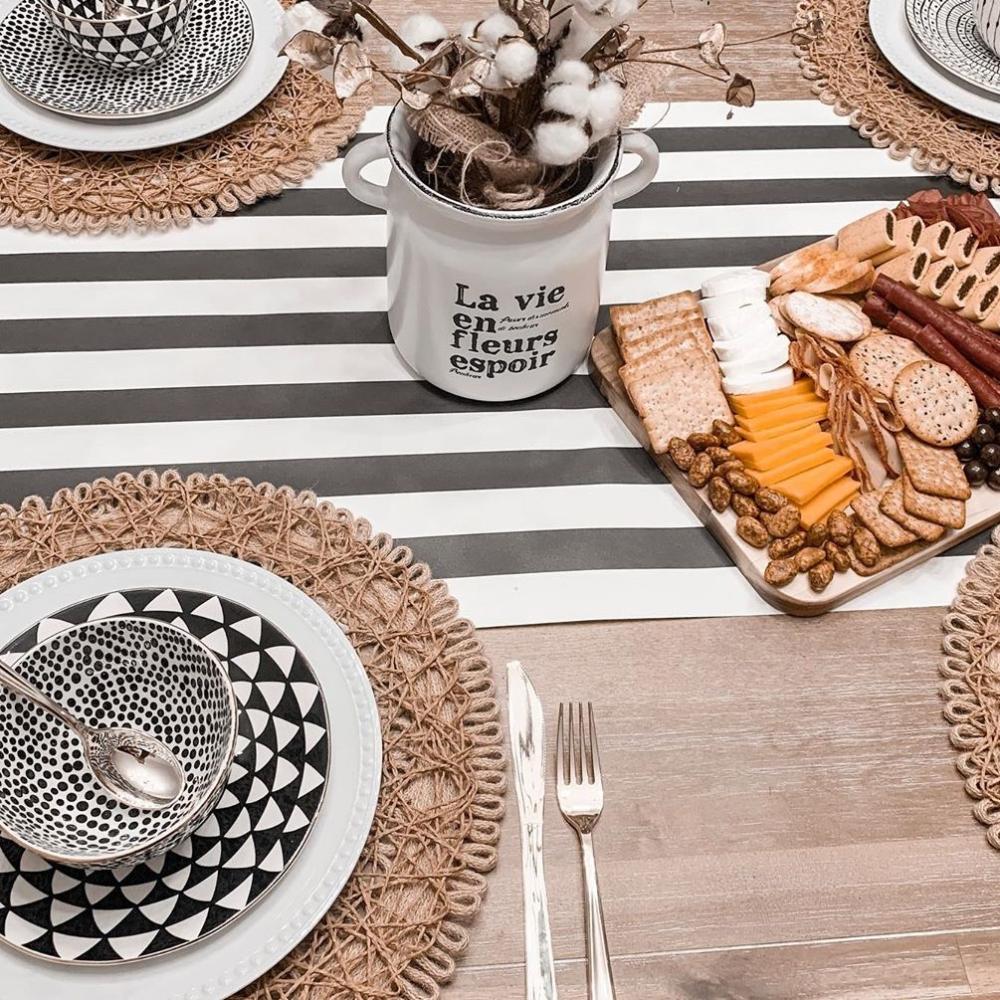 Table setting with black and white striped tablecloth, decorative plates, and a platter of snacks.