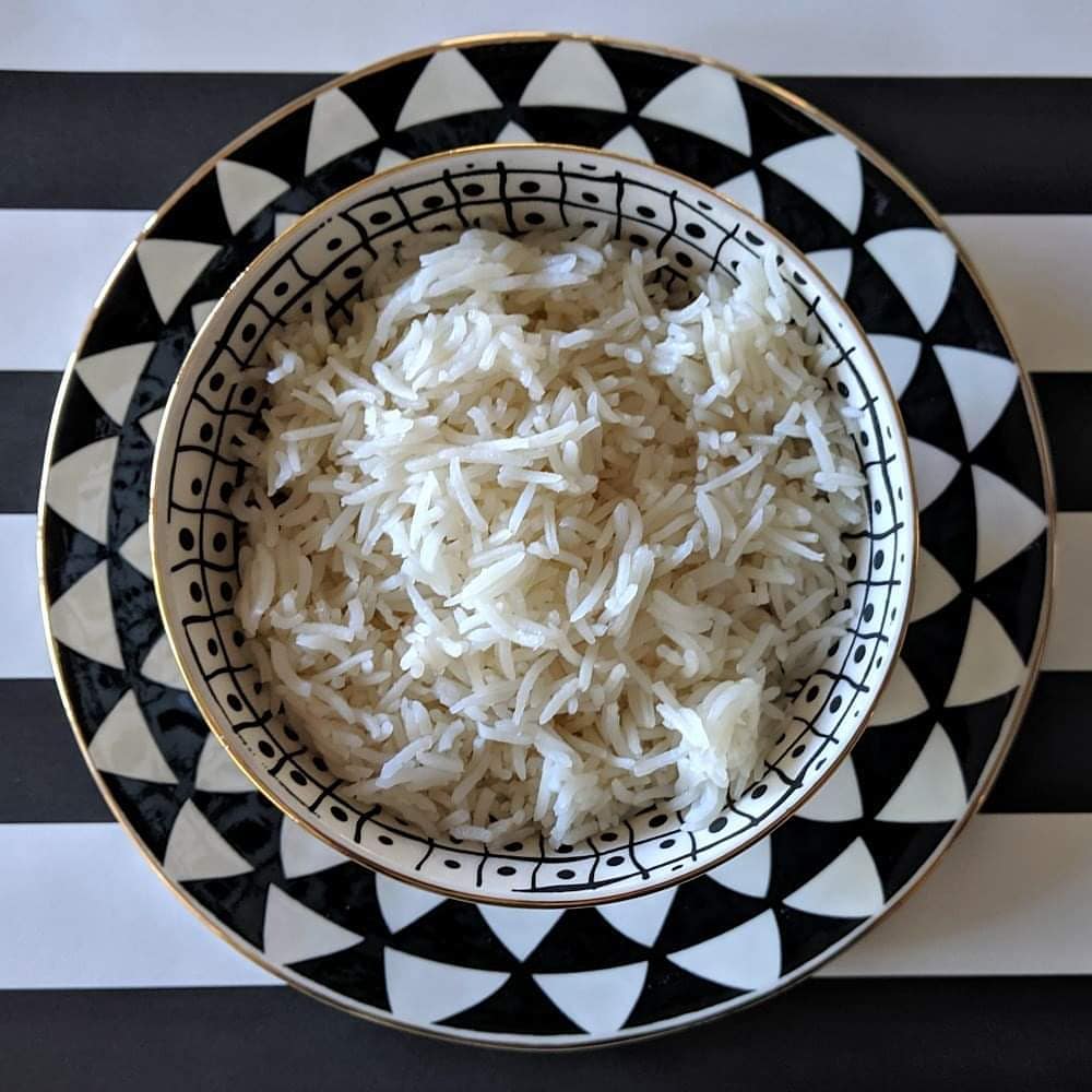 Bowl of white rice on a decorative black and white plate with a striped background