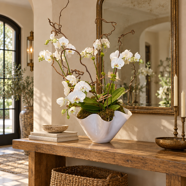 Large Wavy White Bowl filled with orchid stems and curly willow branches on a wooden console table.