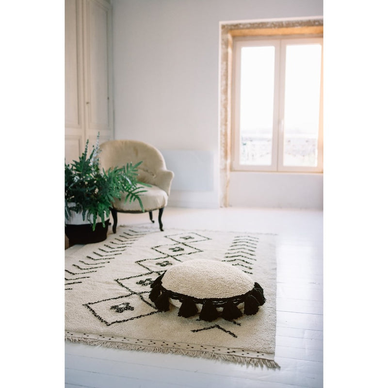 Circle Black Tassel Cushion by Lorena Canals, textured beige with black pom-poms, viewed from above, washable.