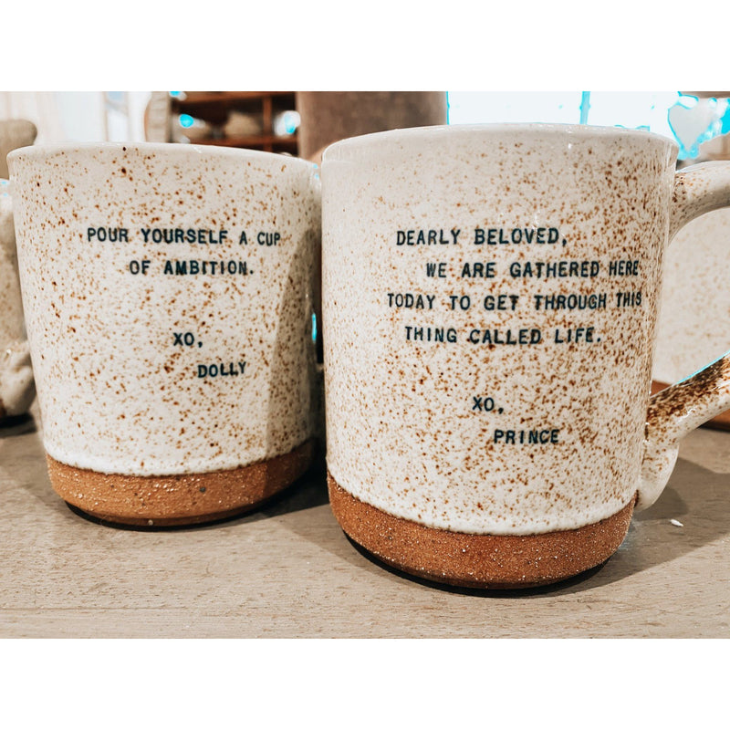 Two whimsical mugs from the XO Legends Coffee Mugs (1st Edition) set by Sugarboo & Co. feature inspiring quotes: one with an ambition-themed Dolly quote and the other with a life-focused Prince quote.