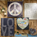 The L-O-V-E Gallery Wrapped Canvas Wall Art Print by Sugarboo & Co. showcases a peace sign, heart, and "LOVE" text on a wood background, offering a retro vibe. It's perfect for enhancing your bedroom with its gentle love quotes, complemented by surrounding plants and decor.
