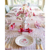 Elegant table setting with a pink floral centerpiece, Abigails Casa Nuno Pink Dinner Plates, glassware, and wrapped gifts.