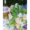 A bouquet of pink frilled tulips arranged in an Abigails Small Ivory Artichoke Tulipiere graces the table, enhancing the elegant dining room display with a bottle of wine subtly nestled in the background.