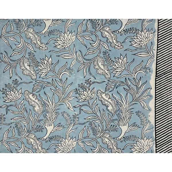 The Flowers + Feathers Cabana Tablecloth by Abigails features a floral pattern with white flowers and leaves on a light blue background, accented by a black and white striped border—ideal for block printing on cotton.