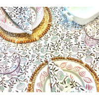 Table setting with floral-patterned tablecloth, plates, hand-woven napkins, Abigails’ Braided Stubble Placemats, and glasses.