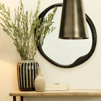 Vase with greenery on a wooden console beside the Constantine Rectangle Decorative Box by Jamie Young, circular mirror above, and a cream resin pendant lamp adding warmth.
