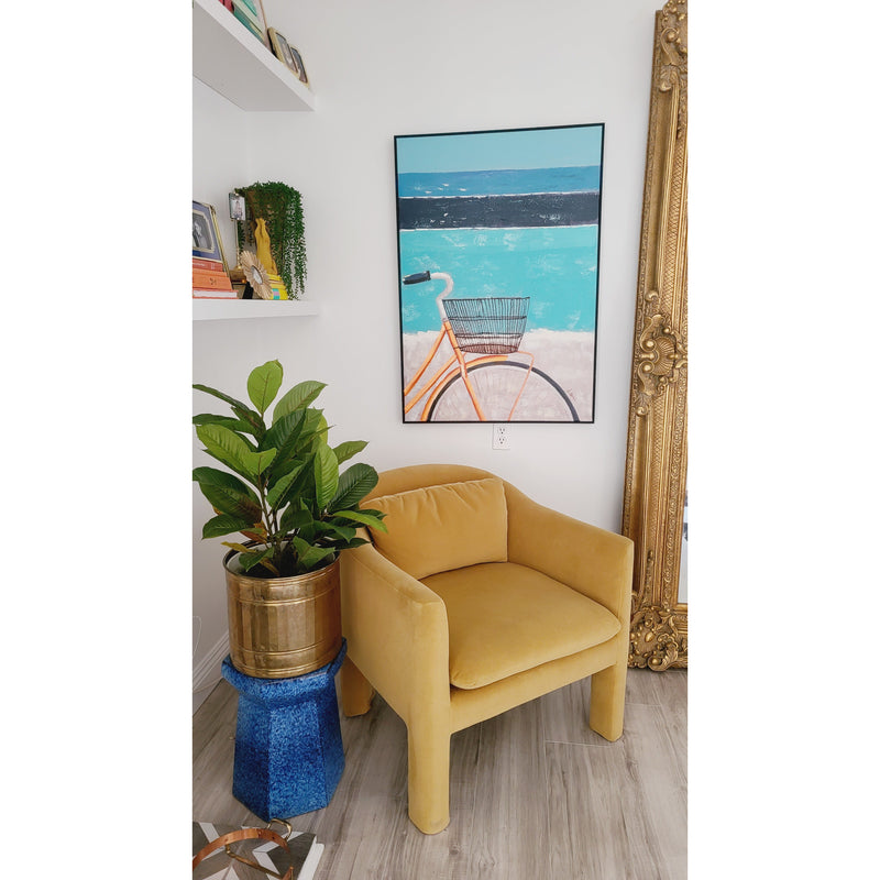A cozy chair next to a potted plant with Kalalou's Oil Painting Bicycle Wall Art framed and a large ornate mirror in the background, perfect for a coastal home.