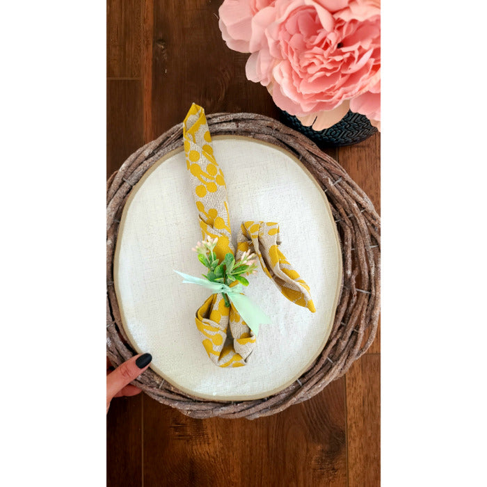 Rustic Grey Twig Charger by Kalalou elegantly placed on a round wicker tray, creating a charming tablescape with pink flowers nearby.