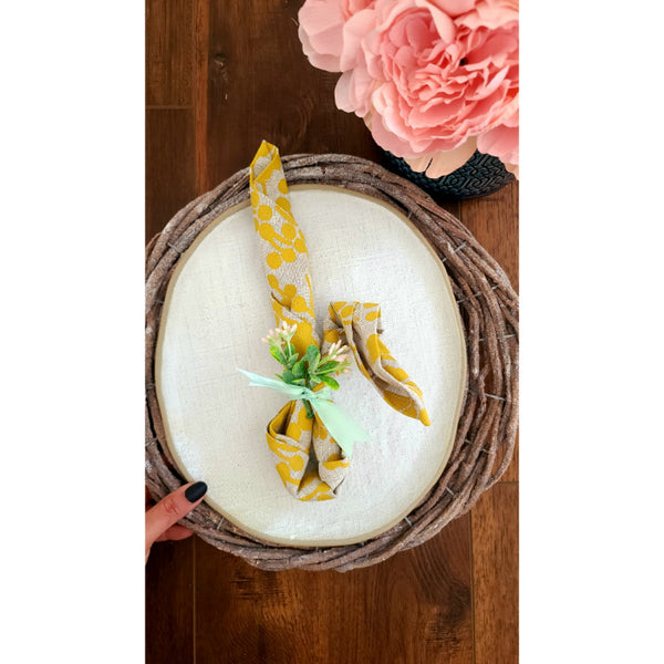 Rustic Grey Twig Charger by Kalalou elegantly placed on a round wicker tray, creating a charming tablescape with pink flowers nearby.
