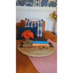 Orange couch with Lacefield Designs' indigo lumbar pillow, flowers, glasses, books on a tray against blue/white wallpaper.