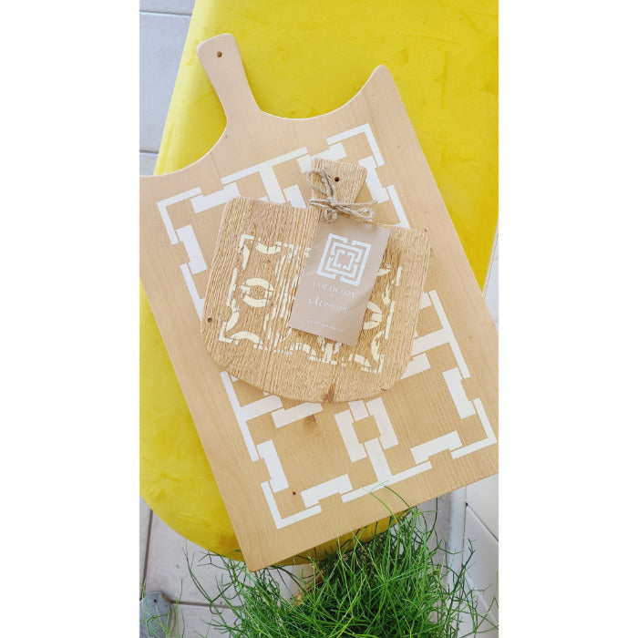 The COCOCOZY Square Link Large Serving Board by BSEID features a white geometric design on reclaimed wood, accompanied by a small decorative item set against a yellow background. Ideal for a modern farmhouse kitchen, this serving board enhances your decor with its unique decorative appeal.