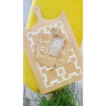 The COCOCOZY Square Link Large Serving Board by BSEID features a white geometric design on reclaimed wood, accompanied by a small decorative item set against a yellow background. Ideal for a modern farmhouse kitchen, this serving board enhances your decor with its unique decorative appeal.