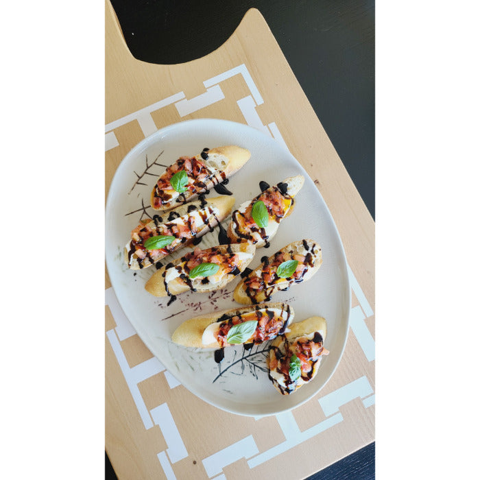 Crostini topped with tomatoes, mozzarella, fresh basil, and balsamic glaze are elegantly presented on the COCOCOZY Square Link Large Serving Board by BSEID. The rustic touch of reclaimed wood adds a decorative layer to this delightful appetizer display.