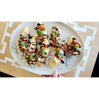 A plate of bruschetta topped with tomato, basil, and balsamic glaze rests elegantly on a COCOCOZY Square Link Large Serving Board by BSEID, enhancing the rustic charm against the wooden table.