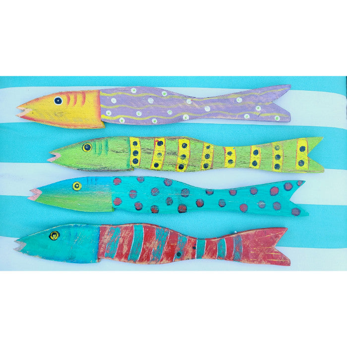 Four colorful wooden fish from the Kalalou Painted Recycled Wood Wall Art set, each uniquely decorated with hand-painted patterns in vibrant tropical colors, are arranged horizontally on a striped blue and white background.
