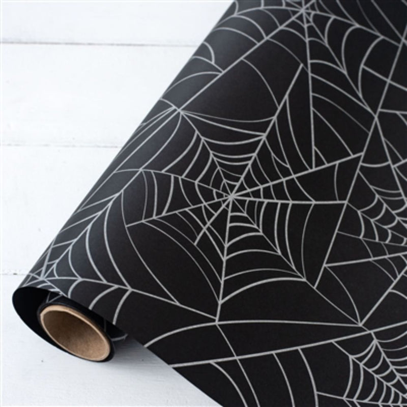 The Halloween Spiderweb Paper Table Runner by Hester & Cook unfurled on a white surface, making it the perfect addition for creating a spooky tablescape at your next Halloween party.