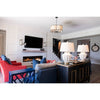 Modern living room with a TV, fireplace, colorful sofas, and Kalalou candle wall sconces by the staircase.