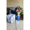 Patio scene with a fade-resistant blue pouf, Newbury Velvet Lumbar by Lacefield, U.S. flags, plant, and white flip-flops.