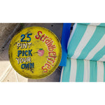 A round Retro Strawberries Metal Tray by BSEID, featuring the vintage message "25¢ pint, pick your own strawberries," adds an old-fashioned flair next to a blue and white striped cushion.