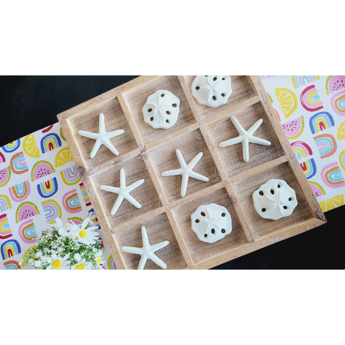 The Tic-Tac-Toe Seaside Game by Kalalou features a beachy vibe with starfish and sea urchins competing on a vibrant patterned backdrop, accented by daisies on the left.