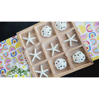 The Tic-Tac-Toe Seaside Game by Kalalou features a beachy vibe with starfish and sea urchins competing on a vibrant patterned backdrop, accented by daisies on the left.