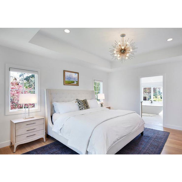 Modern bedroom with a large bed, two bedside tables with lamps, an Arteriors Zanadoo Mid Century Chandelier, and a view of a bathroom.
