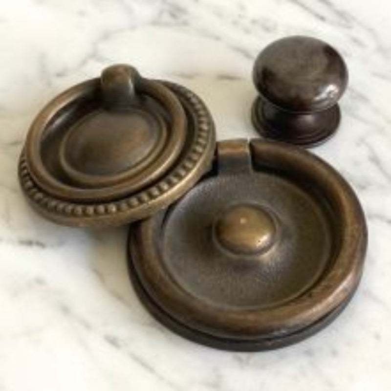 Phillips Scott's Bentley Drawer Buffet features three brass pulls—two circular rings and one round knob—on white marble.