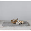 The Travertine Marble Serving Tray by BSEID, featuring a wooden bowl, a bundle of herbs, and round white stones, creates an organic aesthetic on the minimalist surface. The natural vibe is further enhanced by the travertine marble finish, seamlessly blending into any serene space.