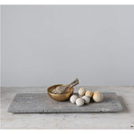 The Travertine Marble Serving Tray by BSEID, featuring a wooden bowl, a bundle of herbs, and round white stones, creates an organic aesthetic on the minimalist surface. The natural vibe is further enhanced by the travertine marble finish, seamlessly blending into any serene space.